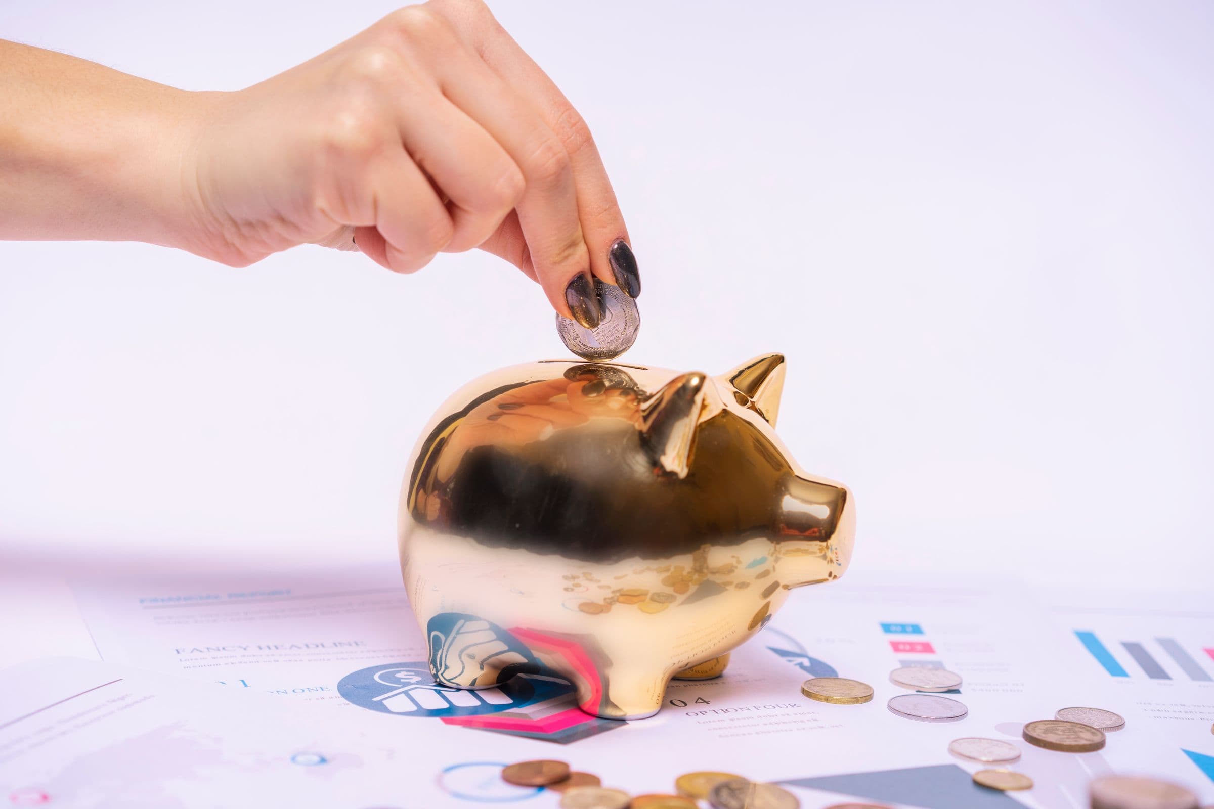 A hand placing a coin into a piggy bank surrounded by financial documents